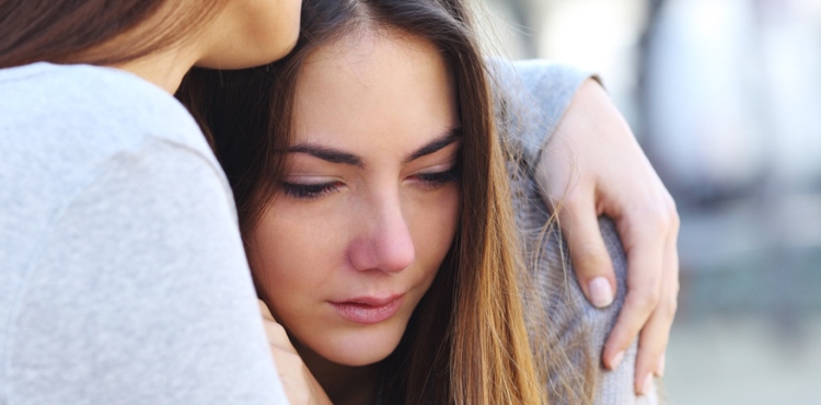 Sad girl crying and a friend comforting her